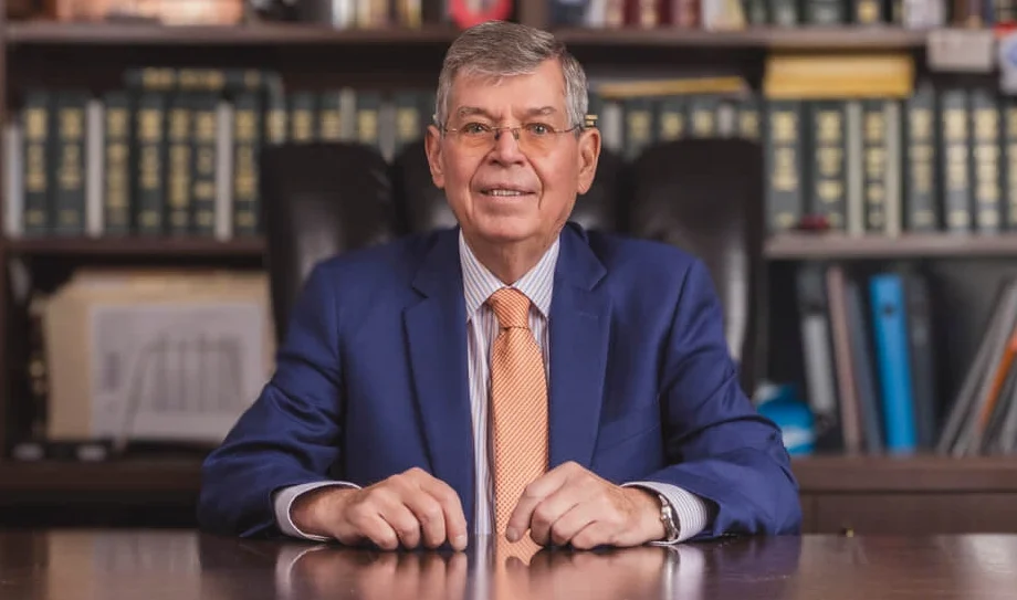 Portrait of Carl McInturff, the founding attorney of McInturff Law Firm, seated at a desk in front of a bookshelf of legal volumes